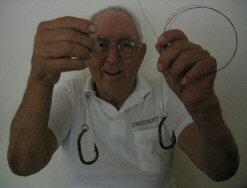 photo of Frank Mundus displaying a couple of environmentally friendly shark hooks